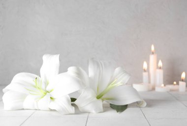 Masasında yanan mumlar olan güzel zambak çiçekleri.