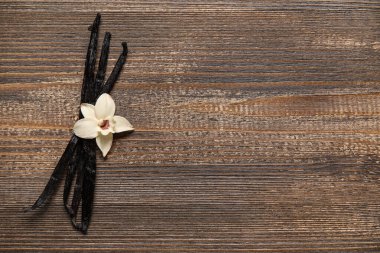 Aromatik vanilya çubukları ve ahşap arka plan üzerinde çiçek