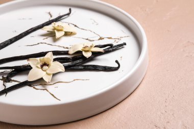 Aromatik vanilyalı tabak ve pembe arka planda çiçekler.