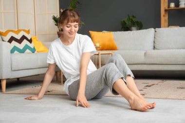 Genç bir kadın evde ısıtmayla yerde oturuyor.