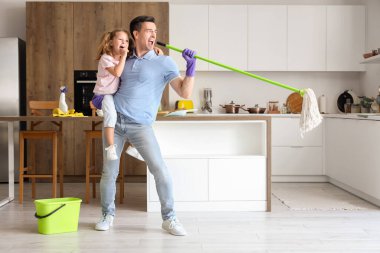 Babası mutfakta yerleri paspaslarken şarkı söyleyen tatlı küçük bir kız.