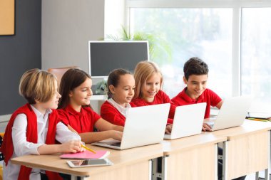 Okulun bilgisayar laboratuvarında laptoplarla çalışan küçük çocuklar.