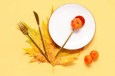 Sarı arka planda akçaağaç yaprağı ve balkabağı ile sonbahar masası ayarları