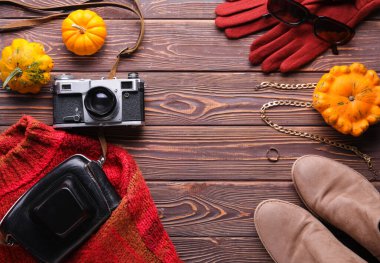 Ahşap arka planda kadın kıyafetleri, aksesuarlar ve balkabaklarıyla kompozisyon