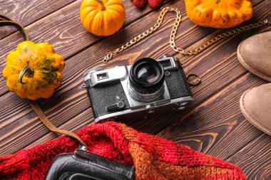 Ahşap arka planda kadın kıyafetleri, aksesuarlar ve balkabaklarıyla kompozisyon