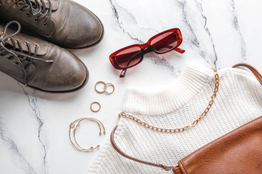Hafif arka planda şık kadın aksesuarları, giysileri ve ayakkabıları olan kompozisyon