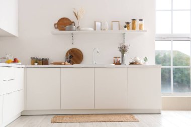 Beyaz tezgahlı, raflı, lavabolu ve çatallı modern mutfağın içi.