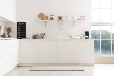 Interior of light kitchen with white counters, shelf, sink and utensils clipart