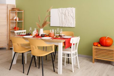 Sonbahar sofrası, balkabakları, kuru yapraklar ve yemek odasında yanan mumlar.