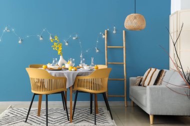 Modern oturma odasında balkabakları ve sarı çiçeklerle sonbahar masası.