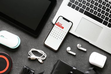 Kasım 2023 için takvimi olan cep telefonu ve koyu arkaplanda farklı cihazlar. Kara Cuma konsepti