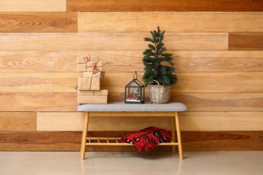 Noel ağacı olan gri bank, hediye kutuları ve ahşap duvarın yanındaki dekor.