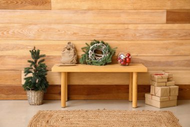 Noel ağacı bankı, hediye kutuları ve ahşap duvarın yanındaki dekor.