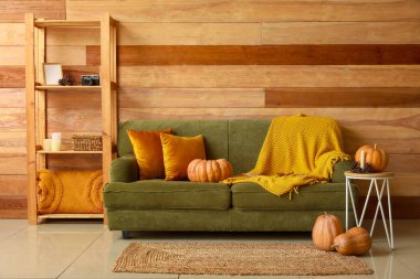 Yeşil kanepeli ve balkabaklı rahat bir oturma odası.