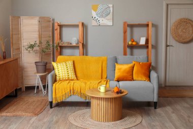 Kahve masasında gri kanepe ve balkabağı olan modern oturma odasının içinde.