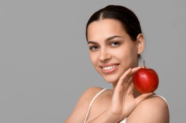 Gri arka planda taze kırmızı elmalı güzel bir kadın.