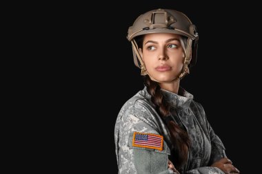Siyah arka planda kolunda Amerikan bayrağı olan kendine güvenen kadın asker.