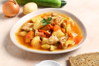 Lezzetli biftek güveci ve bej arka planda farklı malzemelerle dolu bir kase.