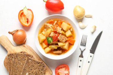 Lezzetli biftek güveci ve beyaz arka planda malzemelerle dolu bir kase.