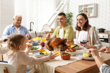Şükran Günü 'nde mutlu bir aile şenlik masasında yemek yiyor.