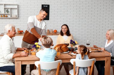 Şükran Günü 'nde mutlu bir aile şenlik masasında yemek yiyor.