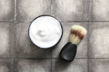 Grunge Grey Fayans arka planında fırçayla tıraş köpüğü kasesi