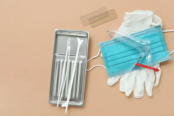 Medical gloves with mask, gynecological speculum and pap smear test tools on brown background