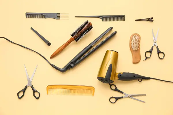 Different hairdressing tools on beige background, top view