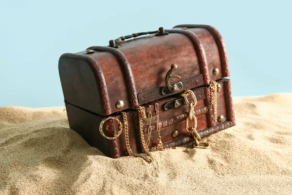 Old chest with treasures on sand against blue background