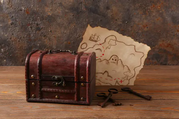 Old chest with keys and treasure map on brown wooden background