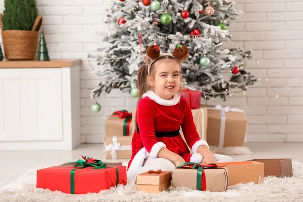 Noel Baba kostümlü, Noel arifesinde evde hediye kutularıyla sevimli küçük bir kız.