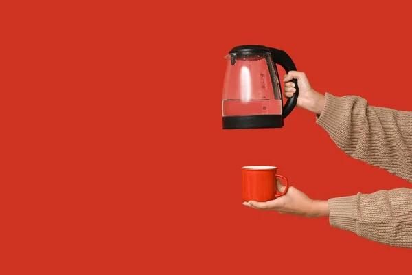 Woman with modern electric kettle on red background