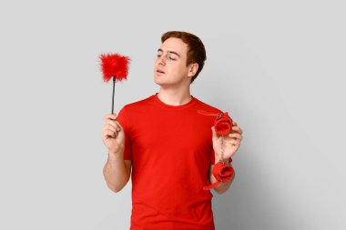 Gri arka planda farklı seks oyuncakları olan yakışıklı bir genç.