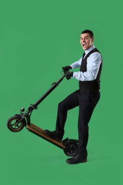 Yeşil arka planda scooter 'ı olan yakışıklı iş adamı.