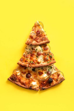 Sarı arka planda pizza dilimleri ve dekordan yapılmış Noel ağacı