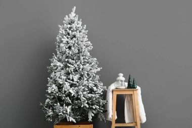 Fenerli ahşap masa ve gri duvarın yanındaki Noel ağacı.