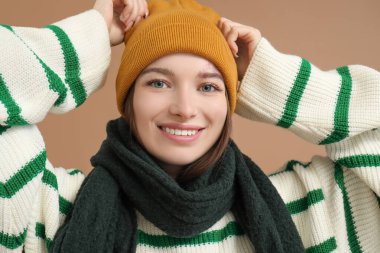 Kahverengi arka planda kışlık elbiseli genç kadın, yakın plan.