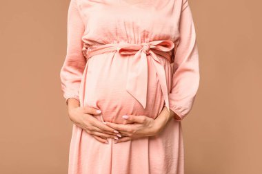 Kahverengi arka planda güzel hamile bir kadın, yakın plan.