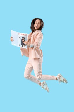Moda dergisinde mavi arka planda zıplayan genç bir kadın.