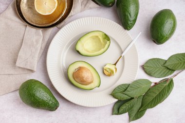 Taze olgun avokado ve beyaz arka planda yapraklarla kaplı tabaklar.