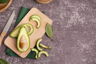 Koyu arkaplanda taze avokado kesilmiş ahşap tahta.