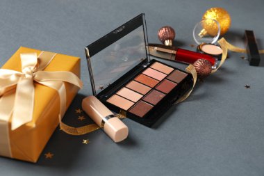 Gri arka planda Noel dekoru ve kozmetik ürünleri içeren kompozisyon