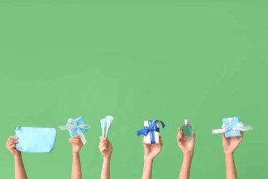 Farklı kozmetik ürünlere sahip kadın elleri ve yeşil arka planda hediyeler