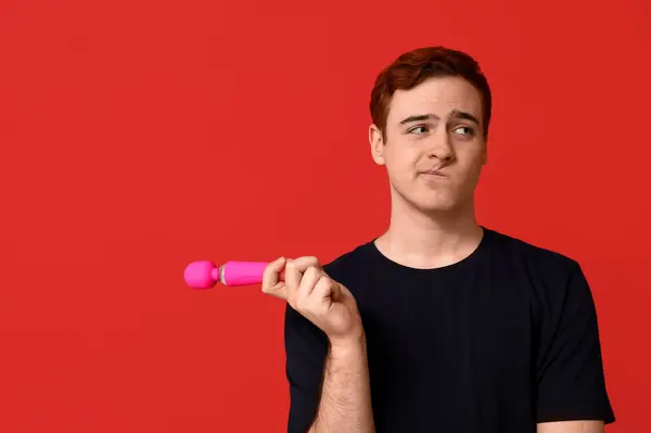 stock image Displeased young man with vibrator on red background