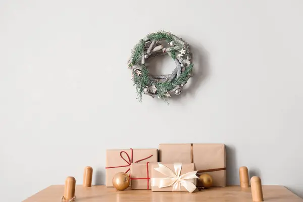 Christmas balls with presents on shelf near light wall
