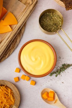 Lezzetli çedar peyniri soslu kase ve beyaz grunge arka planda bir fincan biberiye.