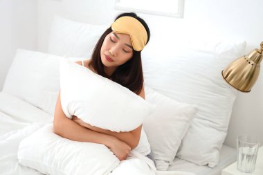 Yatak odasında uyku maskeli güzel bir Asyalı kadın.