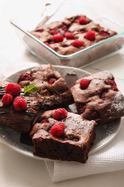 Beyaz arka planda ahudududulu çikolatalı brownie ile tabak ve pişirme tabağı.