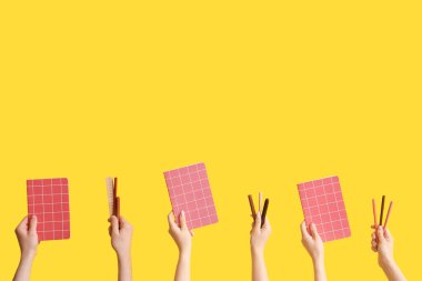 Hands with school supplies on yellow background