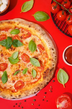 Lezzetli pizza, domatesli Margarita ve kırmızı masada fesleğen.